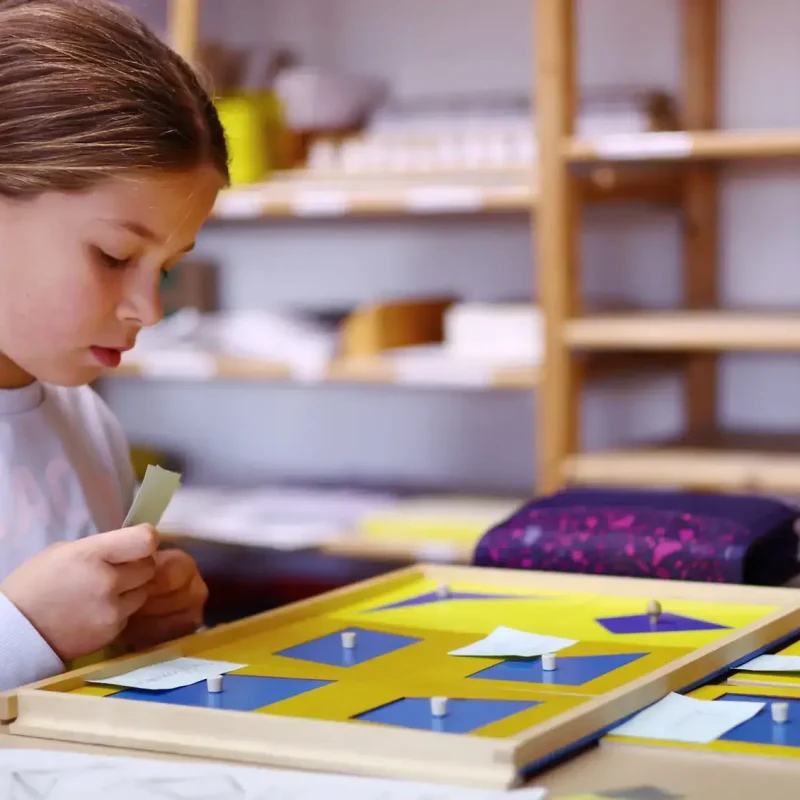 Schülerin arbeitet weiter mit Geometrie-Material und malt Formen aus.