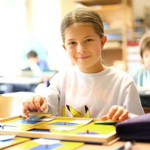 Schülerin lächelt und arbeitet mit Montessori-Materialien für Lesen und Schreiben.