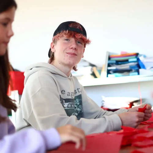 Schüler arbeiten an einer Werkbank und fertigen kleine Holzbauteile an.