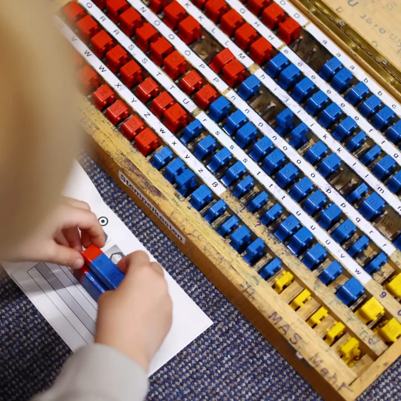 Kind arbeitet mit farbigen Montessori-Buchstaben