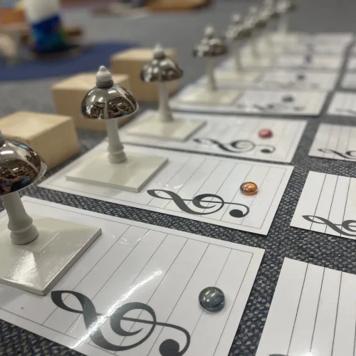 Musikübung Montessori-Klangglocken liegen in einer Reihe auf einem Teppich, bereit zur Musikübung.