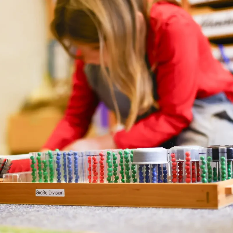 Schülerin sortiert farbige Montessori-Plättchen und übt Mengenverständnis.