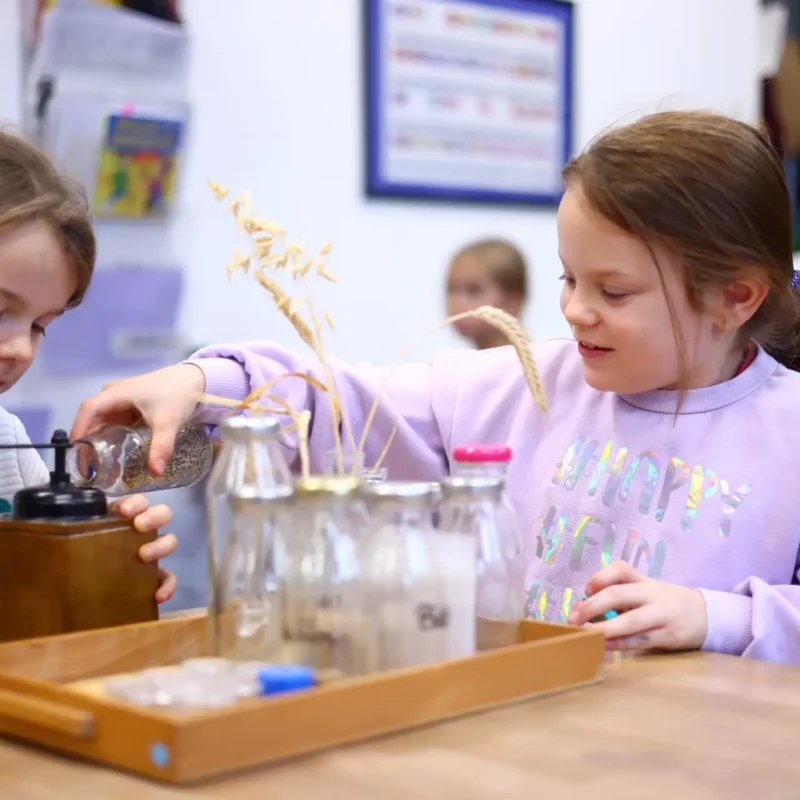 Gruppe von Kindern experimentiert mit Wasser und Glasgefäßen an einem Lernmaterialtisch.