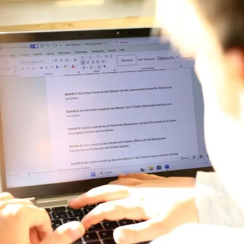 Informatik Unterricht Schule Laptop mit Textdokument, Kind tippt an einer Schreibaufgabe.