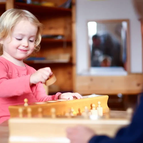 Montessori Kindergarten Zwei Kinder spielen gemeinsam an einem Tisch, während sie Montessori-Material erkunden.