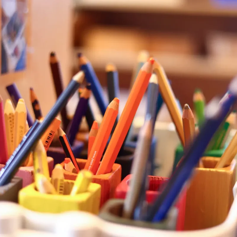 Becher voller Buntstifte in einer vorbereiteten Montessori-Lernumgebung.