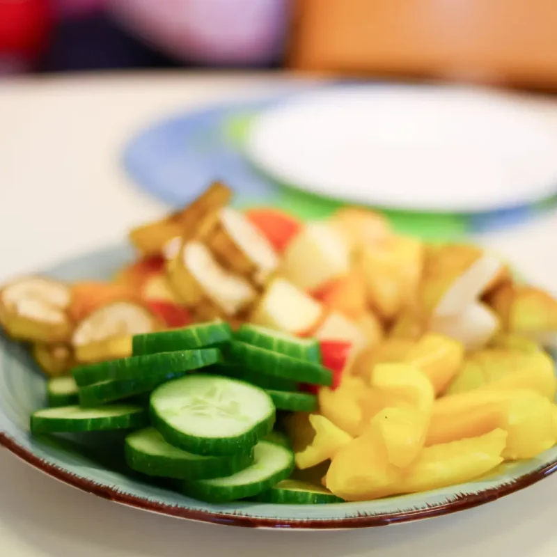Teller mit frischem Gemüse, das Kinder selbst geschnitten und zubereitet haben.