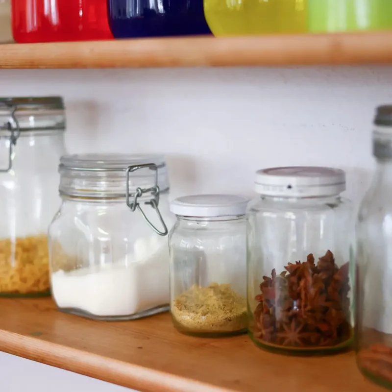 Regal mit verschiedenen Montessori-Gläsern gefüllt mit Materialien für Experimente und Sinnesübungen.