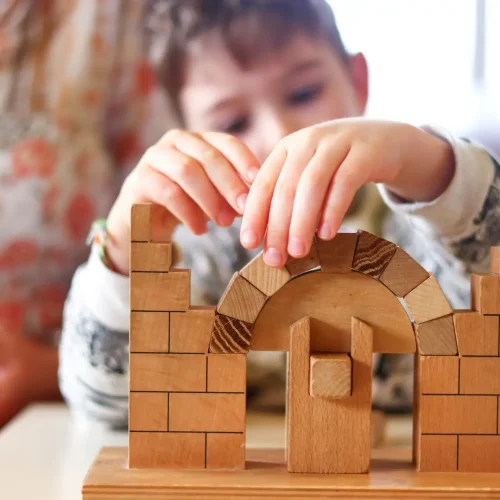 Montessori Kinderhaus Nornheim (74) Kind baut mit Holzbausteinen einen stabilen Bogen und entdeckt statische Prinzipien.