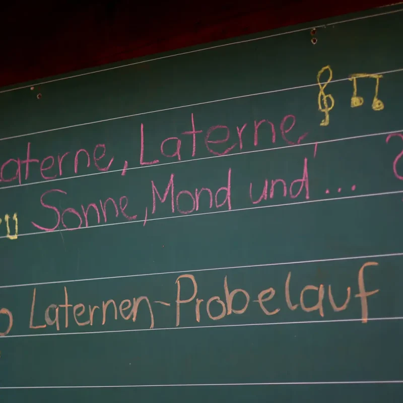 Tafel im Wald mit bunten Kreideschriften zu einem Montessori-Projekt oder Liedtext.