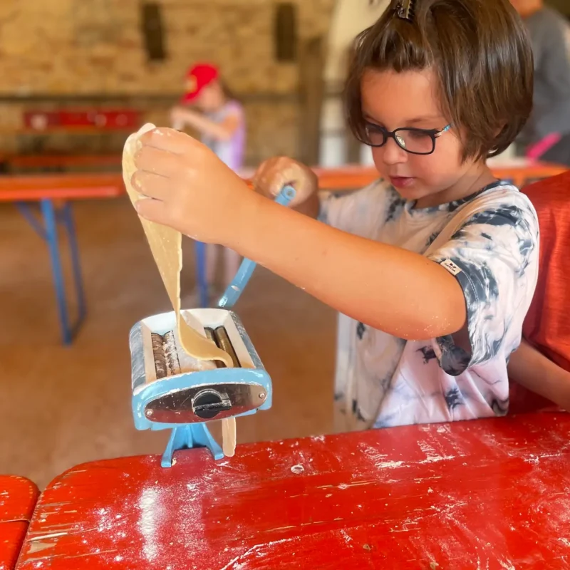 Kind nutzt eine handbetriebene Nudel- oder Tonpresse und setzt Kraft ein.